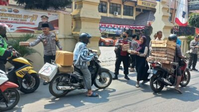 Kapolsek Dukuh Pakis Surabaya Kompol Muhamad Irfan, saat membagikan nasi bungkus kepada para pengendara di depan Mako Polsek Dukuh Pakis Surabaya. (Samsul-harianradar.com).