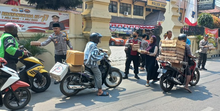 Kapolsek Dukuh Pakis Surabaya Kompol Muhamad Irfan, saat membagikan nasi bungkus kepada para pengendara di depan Mako Polsek Dukuh Pakis Surabaya. (Samsul-harianradar.com).