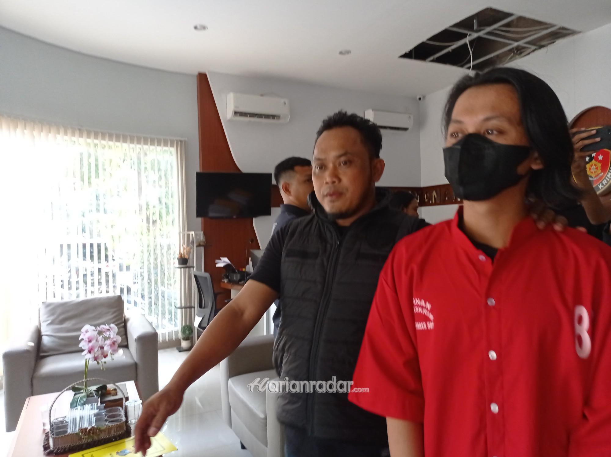 Tersangka RZ memakai baju tahanan warna merah, saat digiring petugas kepolisian menuju sel tahanan mapolrestabes surabaya (foto:samsul-harianradar.com).