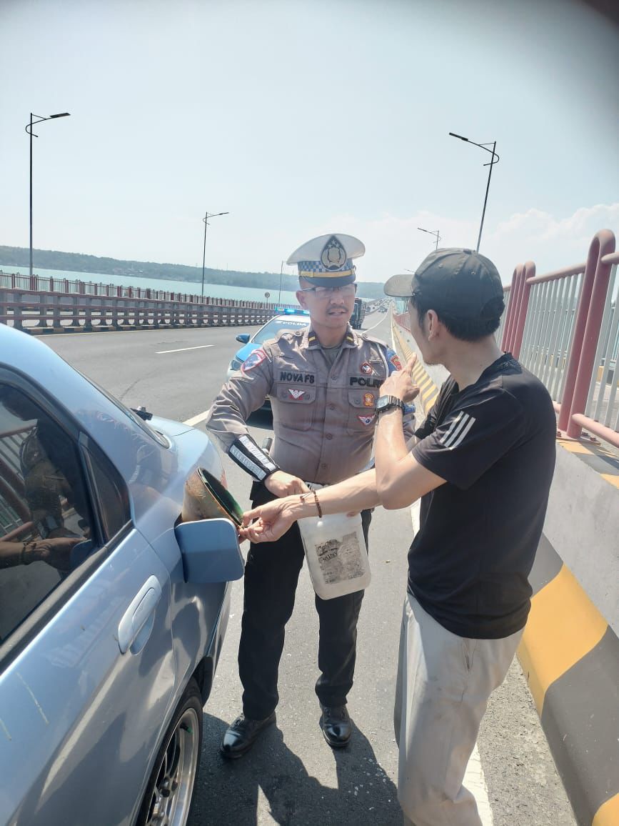 petugas membantu seorang pengendara mobil (R4) yang kehabisan bahan bakar saat melintas di atas Jembatan Tol Suramadu