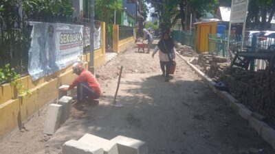 Foto: Pekerja memasang kanstin di lokasi proyek Dakel Kedurus 2A, RW 2, depan SDN Kedurus 1, Kelurahan Kedurus, Kecamatan Karang Pilang, Surabaya. Tampak pemasangan dilakukan langsung di atas tanah tanpa lapisan pasir urug.