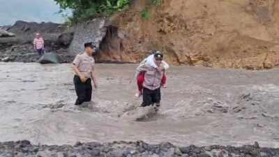 Anggota Polsek Candipuro, Polres Lumajang, turun langsung membantu para pelajar menyeberangi derasnya aliran lahar dingin di Sungai Regoyo