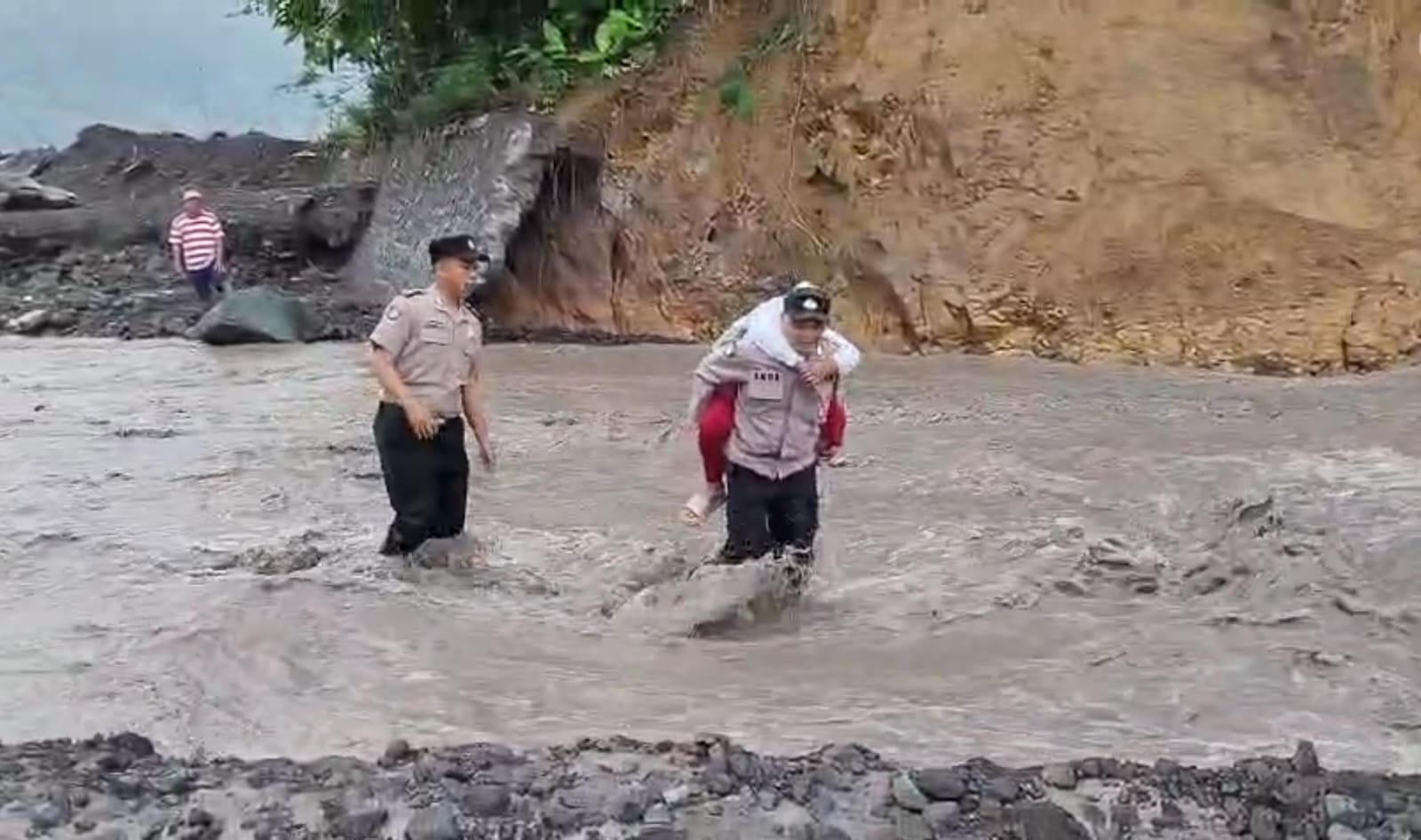 Anggota Polsek Candipuro, Polres Lumajang, turun langsung membantu para pelajar menyeberangi derasnya aliran lahar dingin di Sungai Regoyo
